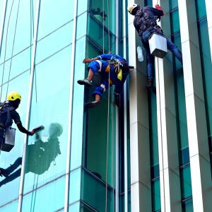 optimalkan-kebersihan-kantor-dengan-memahami-perbedaan-34153042 Petugas profesional melakukan SOP pembersihan kaca gedung tinggi bertingkat dengan aman.